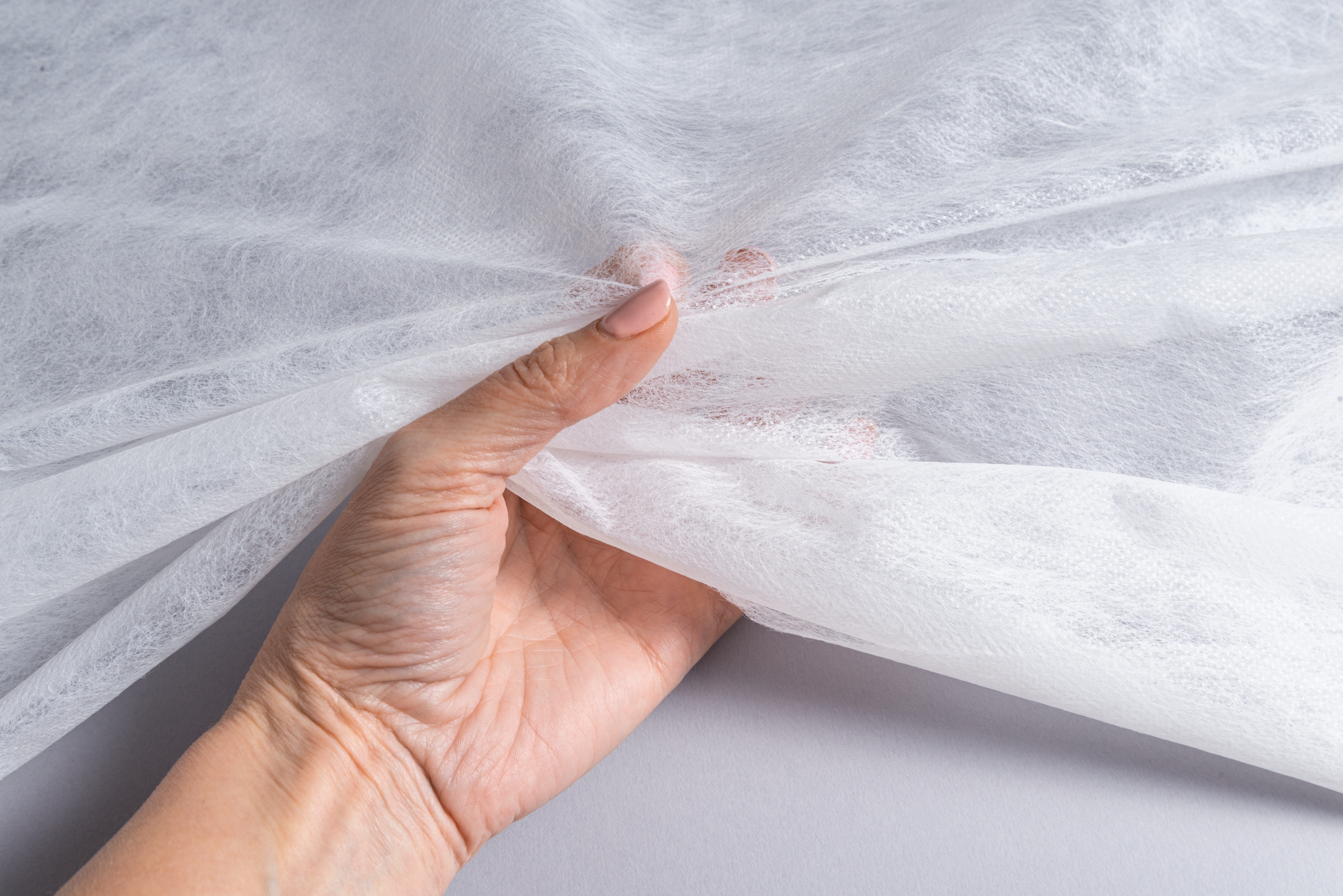 Hands touching a white fiber sheet