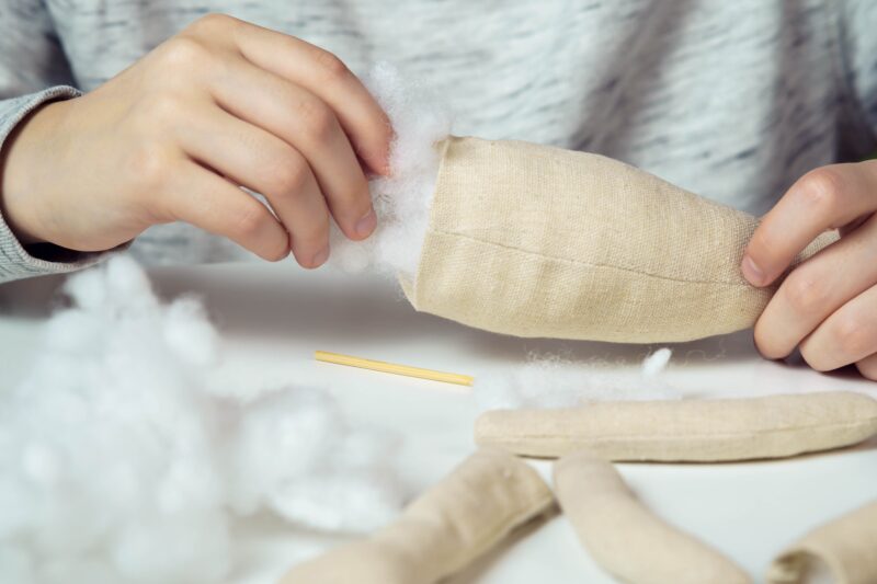 Image of a person stuffing a textile item with cotton filling